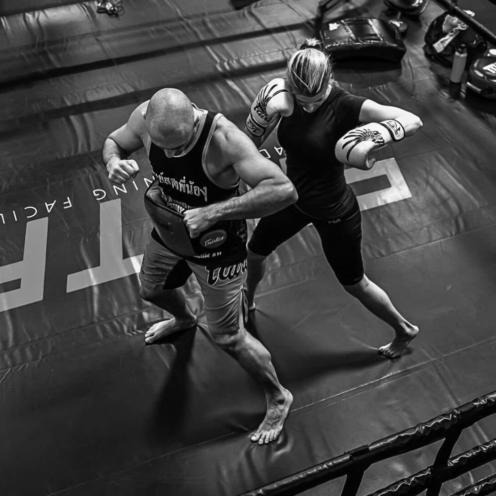 Coach in a belly pad taking a punch from a single student