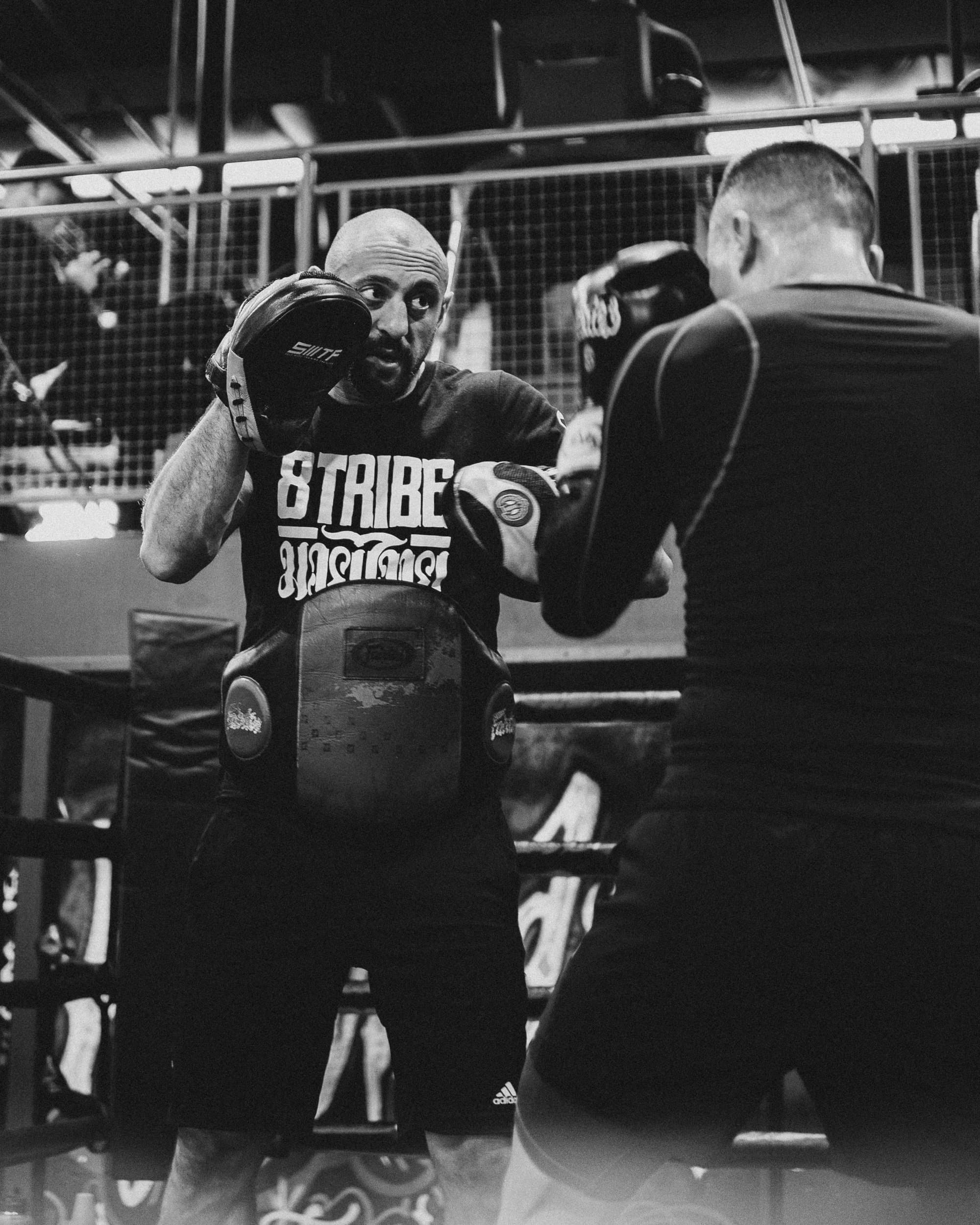 Coach holding pads one to one under low light
