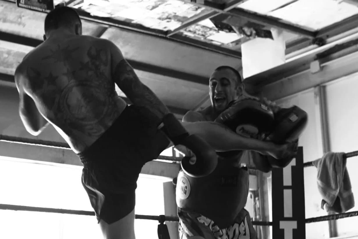 Coach holding pads for a student mid-kick during an all-levels class